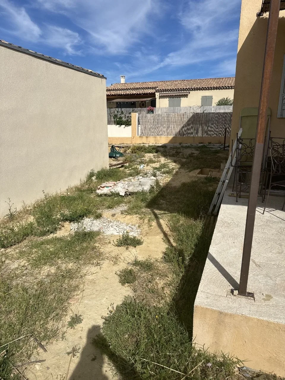 Photo de chantier : terrain en friche entre deux murs, avant décaissement